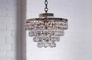 Modern Chandelier Lighting with layers of bubble venetian cristale glass hanging in seven layers against a brick wall