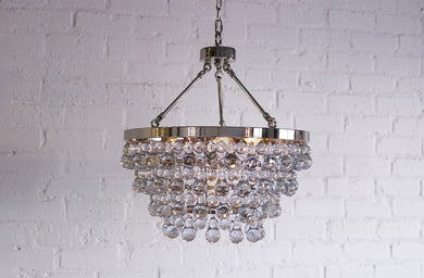Modern Chandelier Lighting with layers of bubble venetian cristale glass hanging in seven layers and 17 inches across against brick wall
